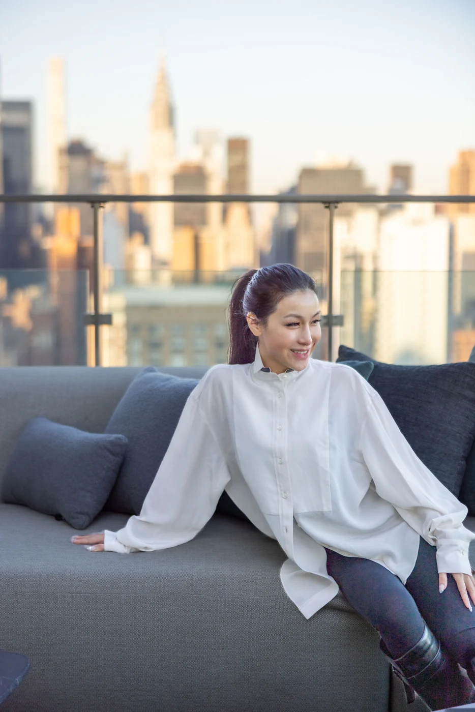 Chelsea smiling on a rooftop in a white shirt