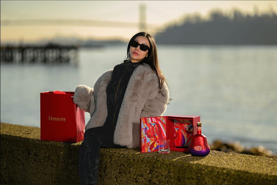 Chelsea beside red Hennessy gift packaging by the water