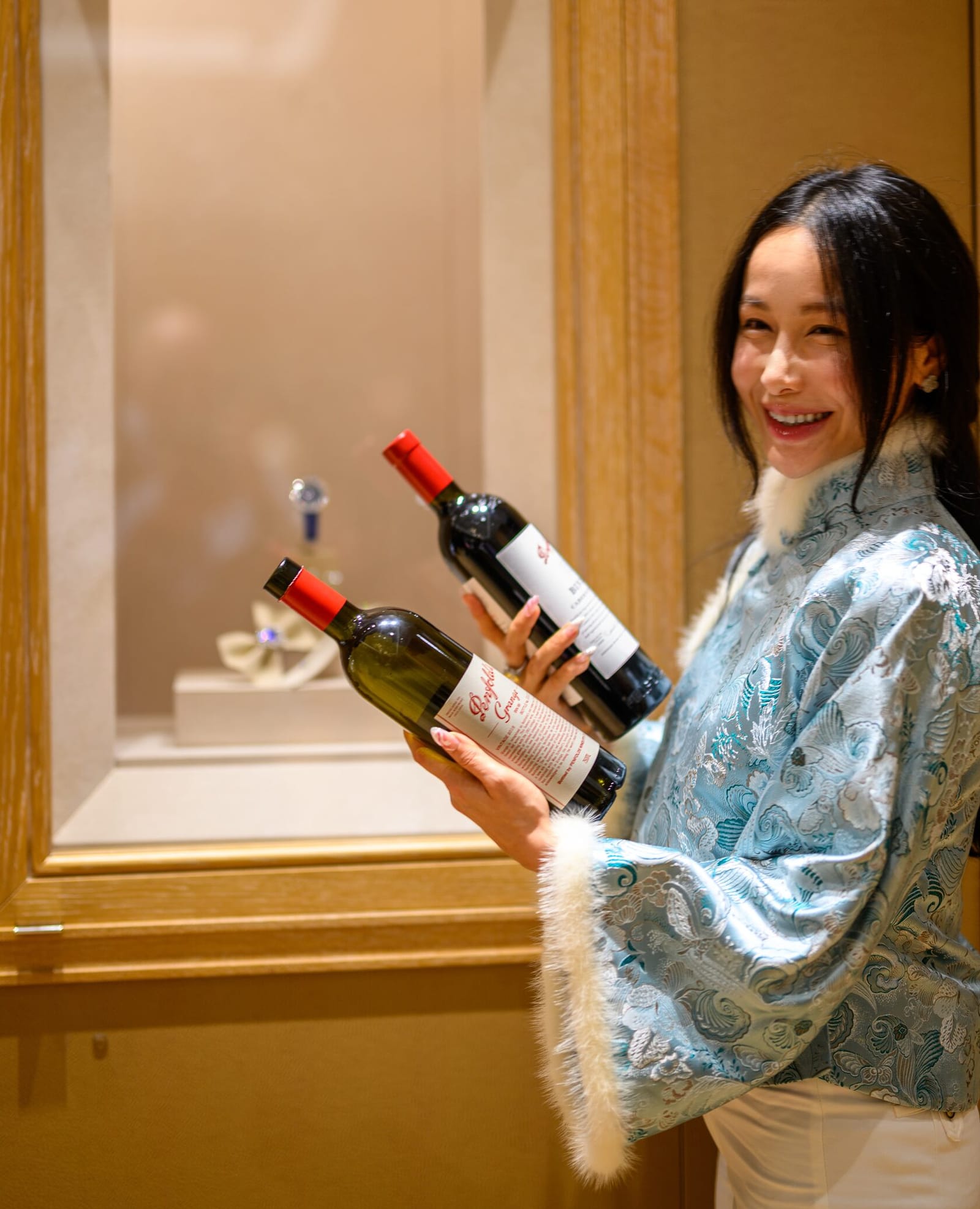 Chelsea smiling while holding two wine bottles